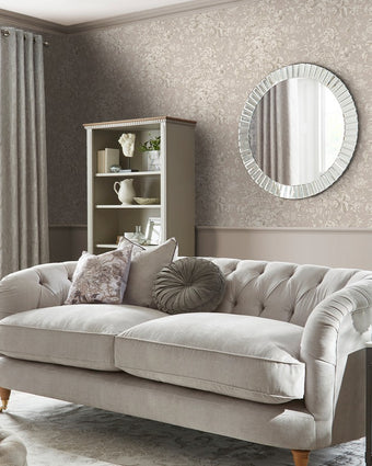 Heledd Blooms Dove Grey Wallpaper on a wall behind a silver mirror, book case and couch