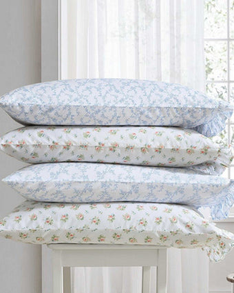 Roseford Cotton Percale White and Soft Orange Sheet Set Pillows stacked on chair