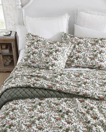 Bramble Floral Green Cotton Reversible Quilt Set close up  view of quilt and shams on a bed