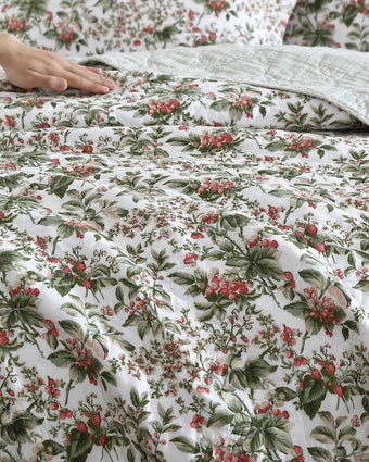 Bramble Floral Green Cotton Reversible Quilt Set close up view of quilt and shams on a bed