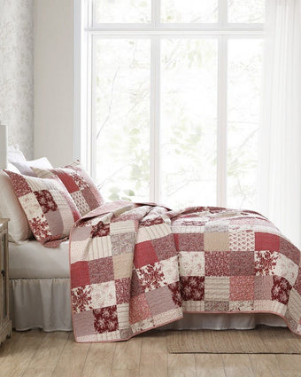 Celina Patchwork Cranberry Cotton Reversible Quilt Set side view of quilt and shams on a bed