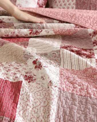 Celina Patchwork Cranberry Cotton Reversible Quilt Set close up view of quilt and shams on a bed