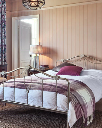 Chalford Wood Panelling Plaster Pink Wallpaper on a wall in a bedroom with a metal bed and white bedding