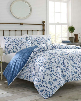 Elise Blue Duvet Cover Bonus Set on a bed in a room with white walls and small window