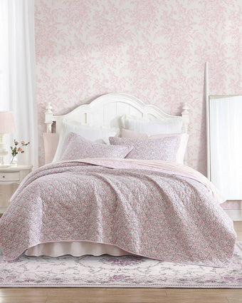 Loveston Pink Reversible Quilt Set - View of quilt and shams on a bed