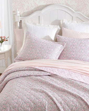 Loveston Pink Reversible Quilt Set - Close up view of shams and quilt on a bed
