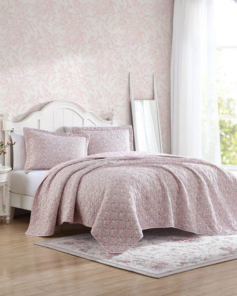 Loveston Pink Reversible Quilt Set - View of quilt and shams on a bed