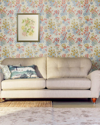 Megan Ochre Yellow Wallpaper on a wall behind a neutral couch