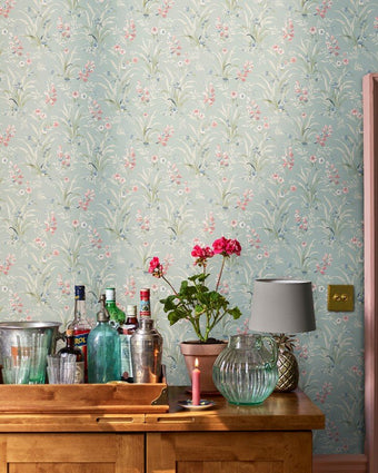 Posy Dark Duck Egg Blue Wallpaper on a wall behind florals and lamp