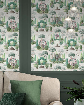Naunton Folly Fern Green Wallpaper on a wall behind a neutral couch and green cushions