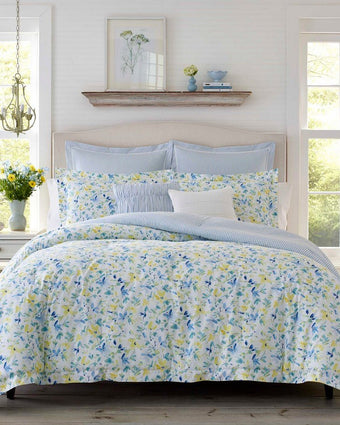 Nora Sun Blue Comforter Bonus Set on a bed in a room with decor and two windows