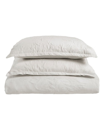 Rowland White Matelasse Duvet Cover Set - View of folded duvet cover and 2 pillow shams with pillows in them