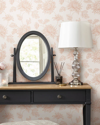 Stratton Plaster Pink Wallpaper on a wall behind a mirror , lamp and table