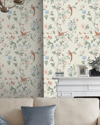 Summer Palace Sage and Apricot Wallpaper on a wall behind a couch