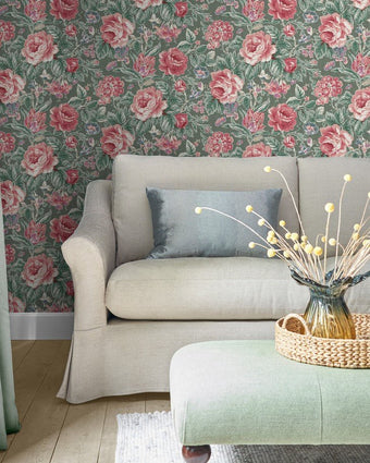 Wild Roses Fern Green Wallpaper on a wall behind a grey couch