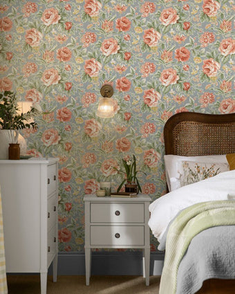 Wild Roses Ochre Yellow Wallpaper on a wll in a bedroom with white tables and wood bed.